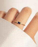 Gold ring with a sapphire blue baguette gemstone models hand
