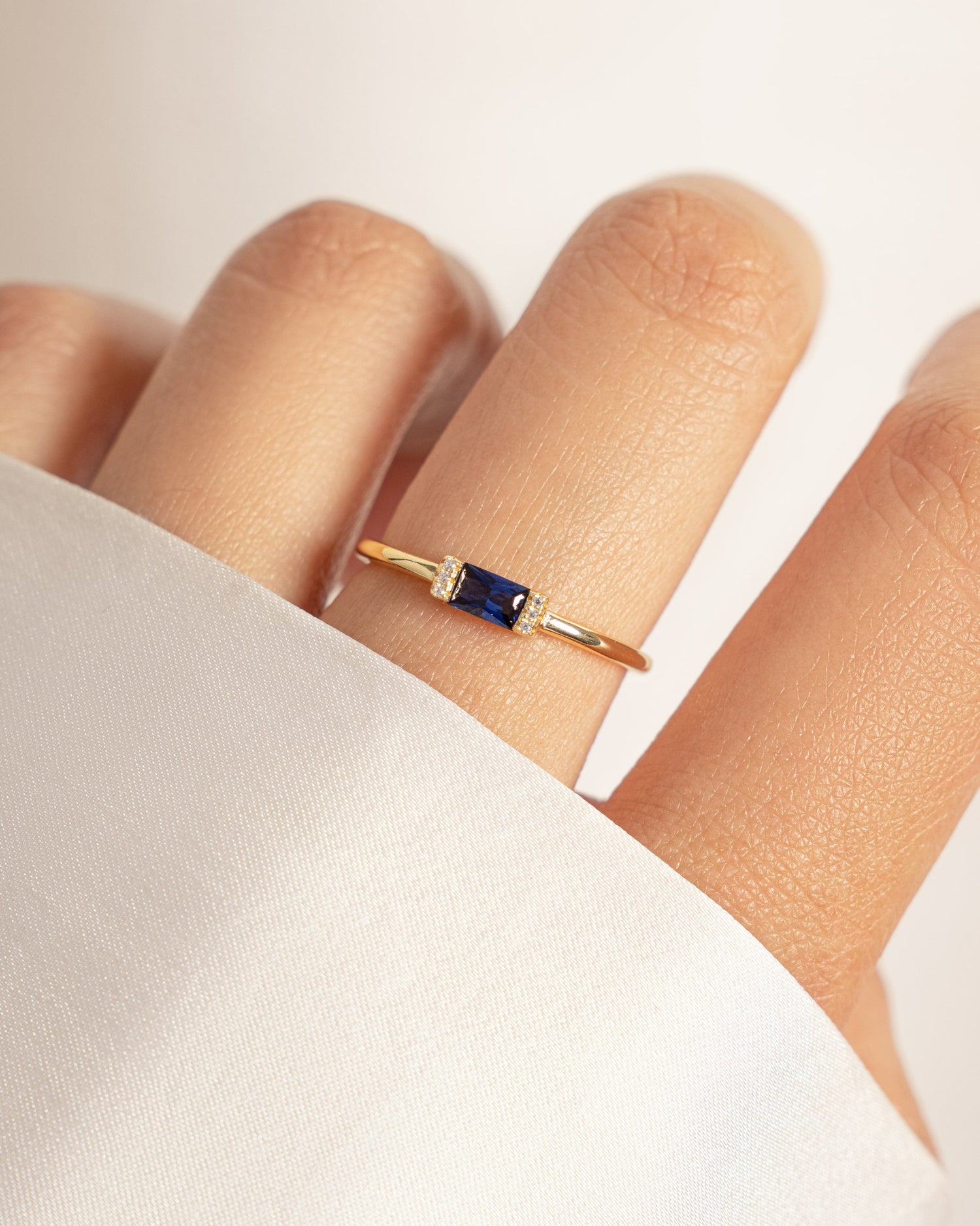Gold ring with a sapphire blue baguette gemstone models hand