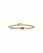 Gold bracelet with a sapphire gemstone on a white background