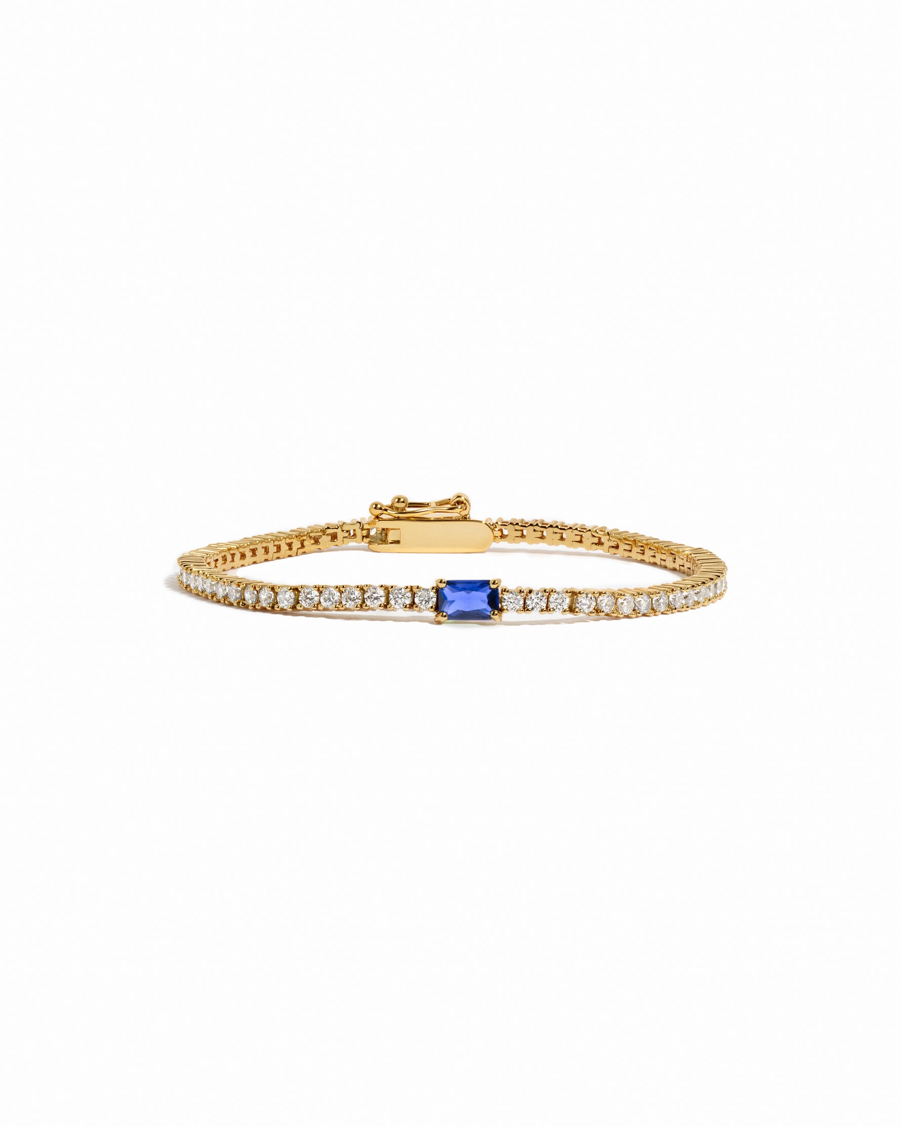 Gold bracelet with a sapphire gemstone on a white background