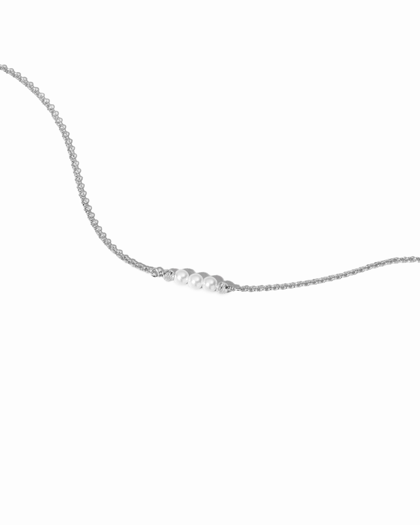 Delicate silver bracelet with small pearls on a white background