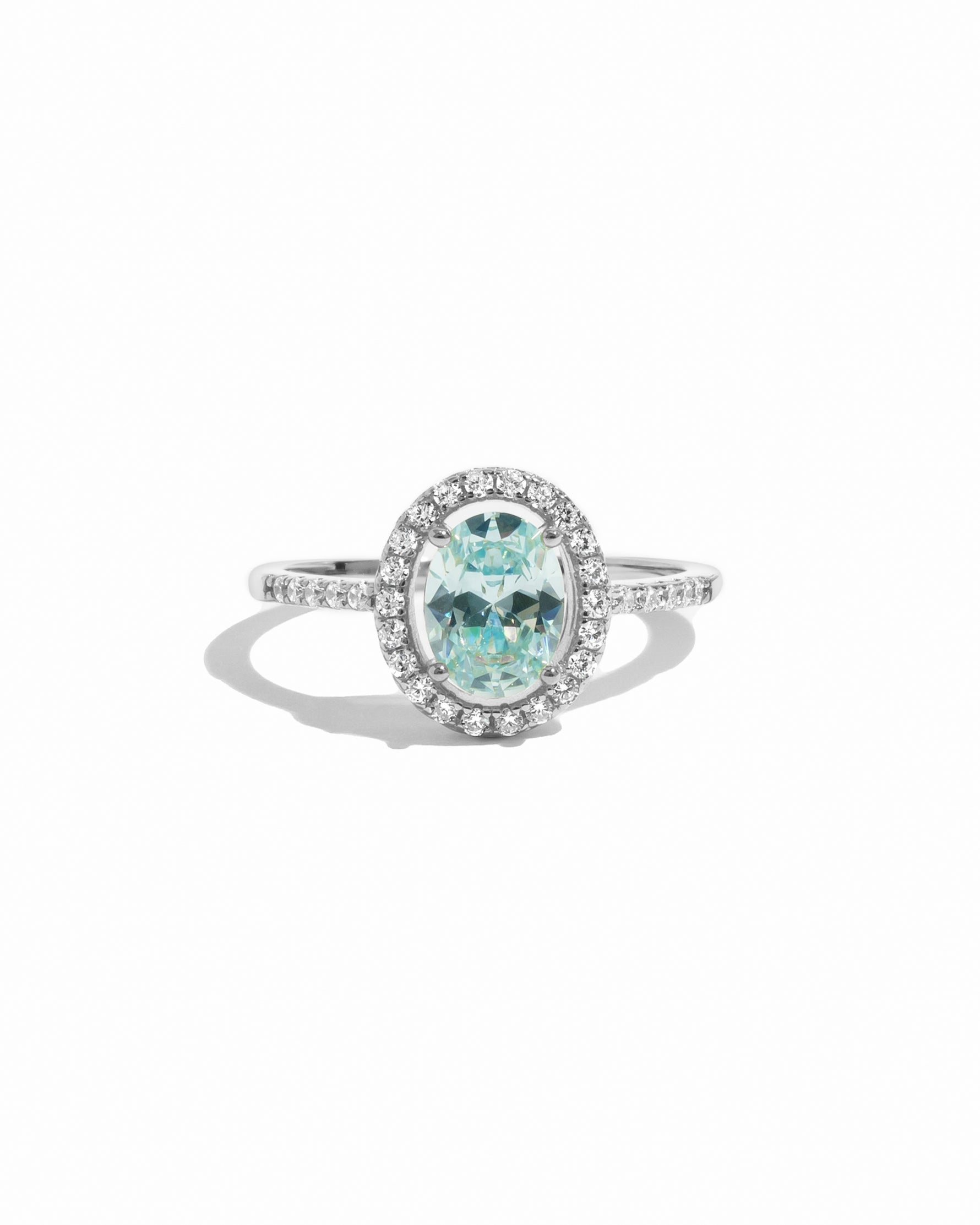 Silver ring with a aquamarine gemstone and diamond-studded halo on a white background