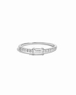 Silver ring with small diamonds and a central baguette diamond on a white background