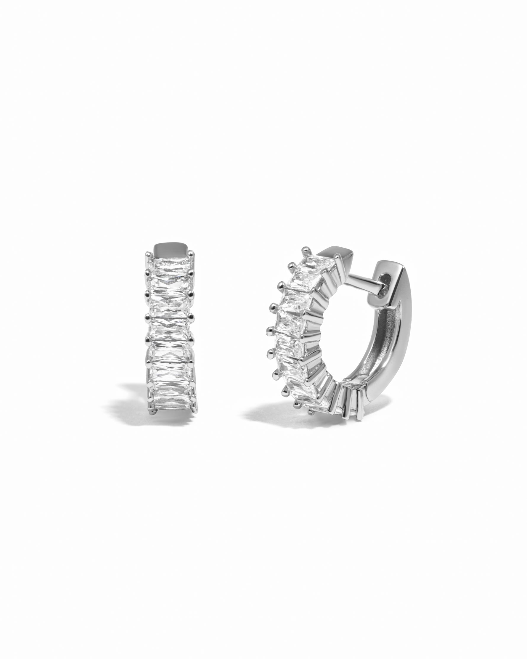 Pair of silver huggies with baguette-cut cubic zirconia stones on a white background