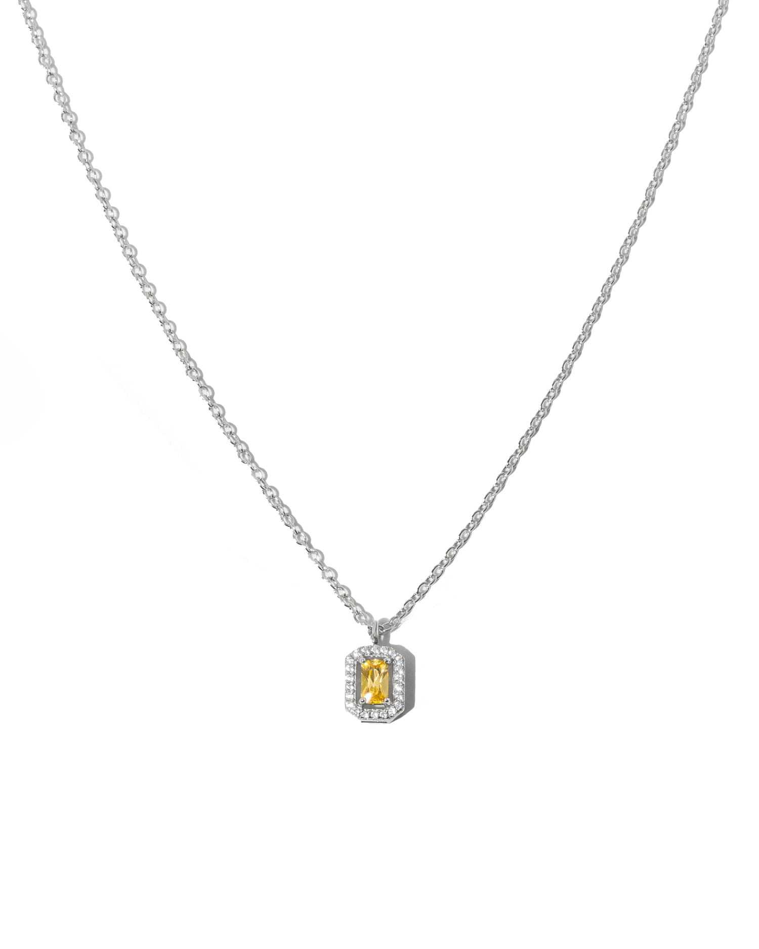 Silver chain necklace with a yellow gemstone pendant on a white background
