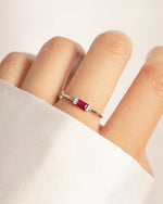 model wearing baguette ring with cubic zirconia pave stones and a baguette ruby stone