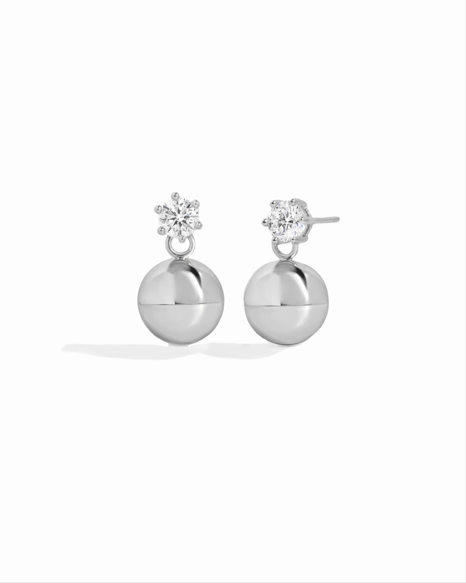 close up of diamond stud earrings with small silver ball earrings