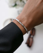 Model wearing sterling silver bangle bracelet with bezel set cubic zirconia diamonds