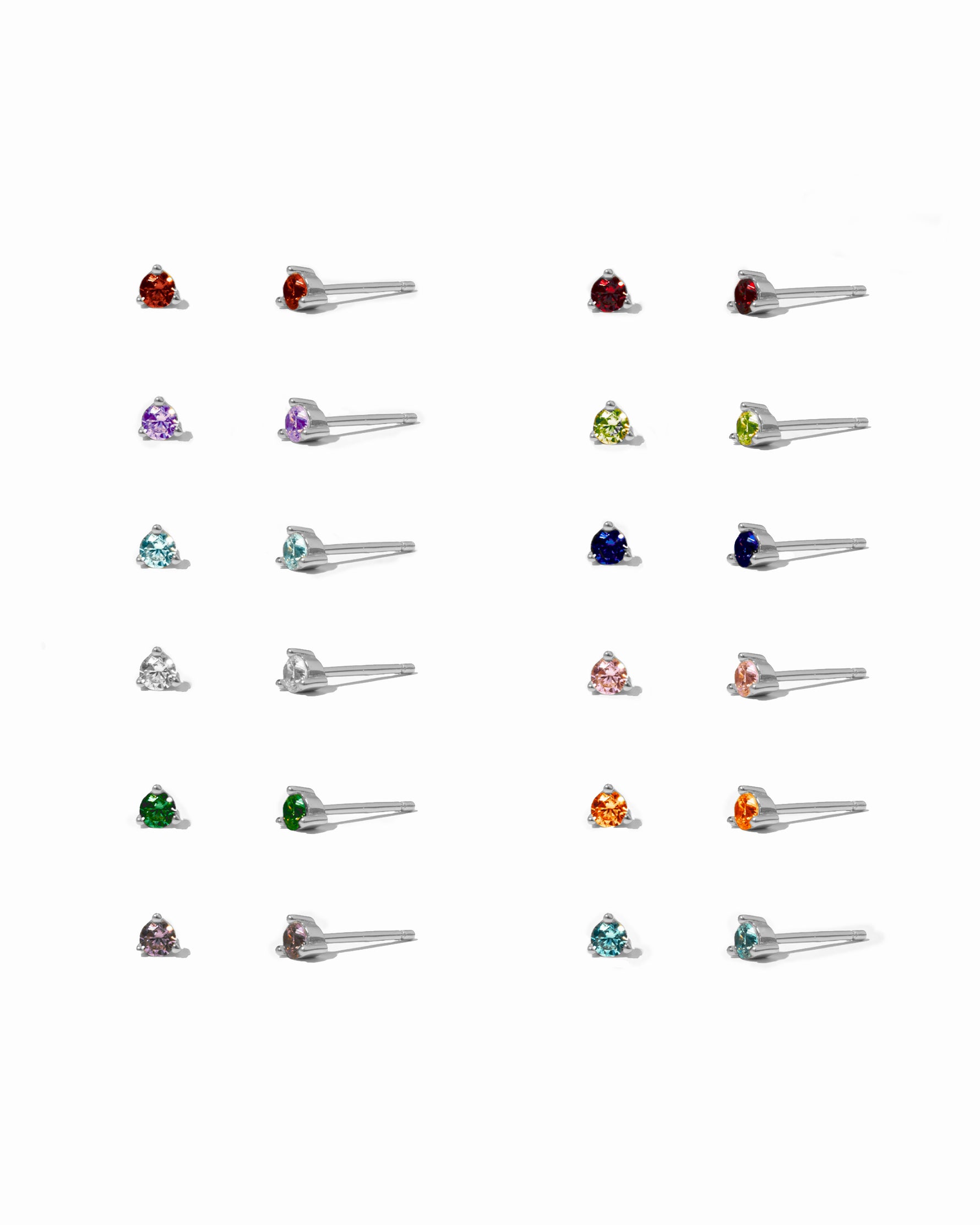 Collection of sterling silver dainty stud earrings with different birthstone colored stones on a white background