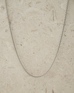 Silver box chain necklace on a beige background