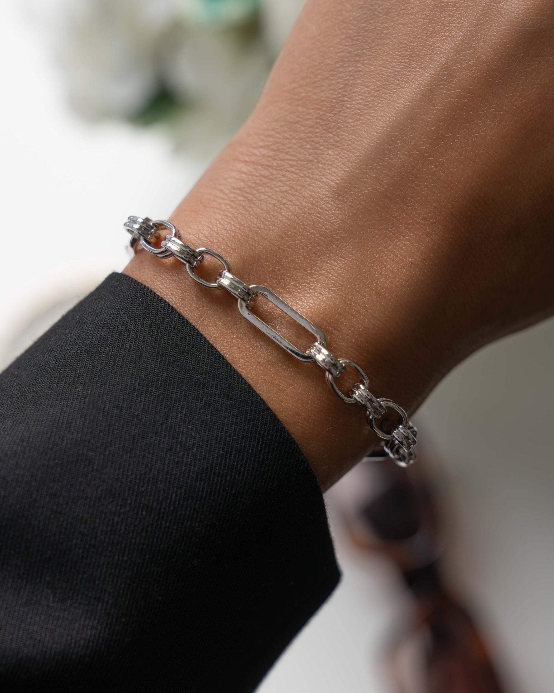 Silver chain adjustable bracelet on a wrist with a blurred background