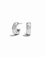 Pair of silver small hoop earrings earrings with a white cubic zirconia stone on a white background