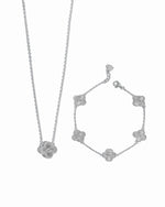 Silver clover pendant necklace and bracelet set on a white background