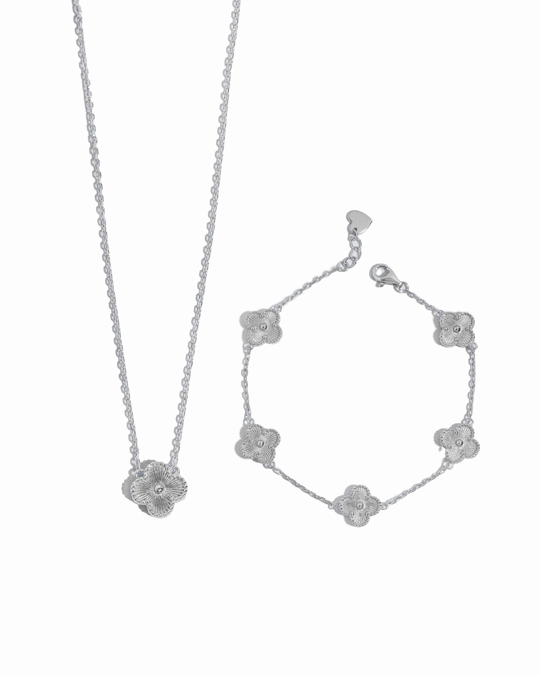 Silver clover pendant necklace and bracelet set on a white background