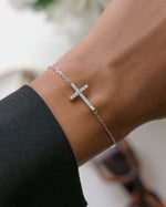 Silver chain bracelet with a cross bracelet design on a wrist 