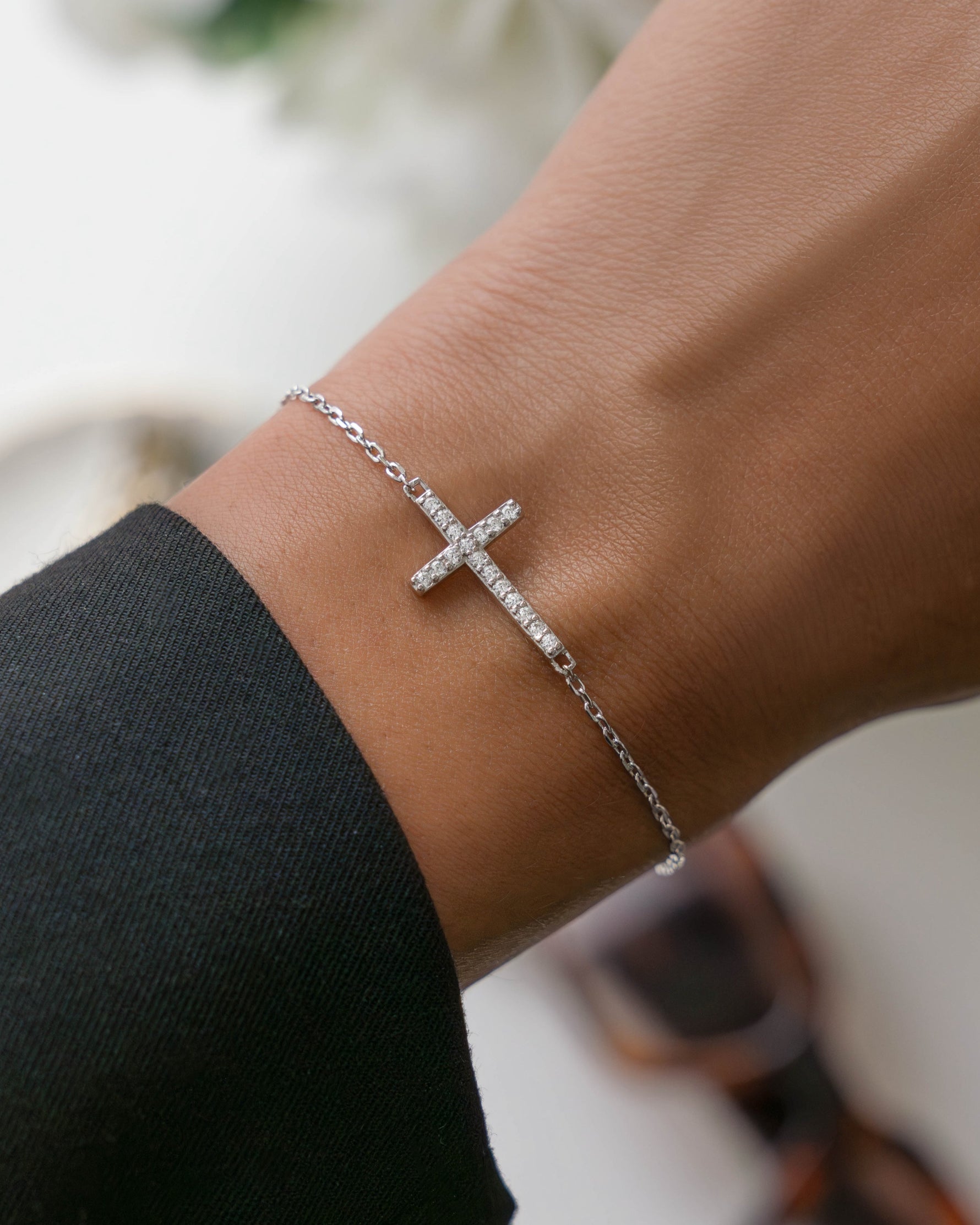 Silver chain bracelet with a cross bracelet design on a wrist 