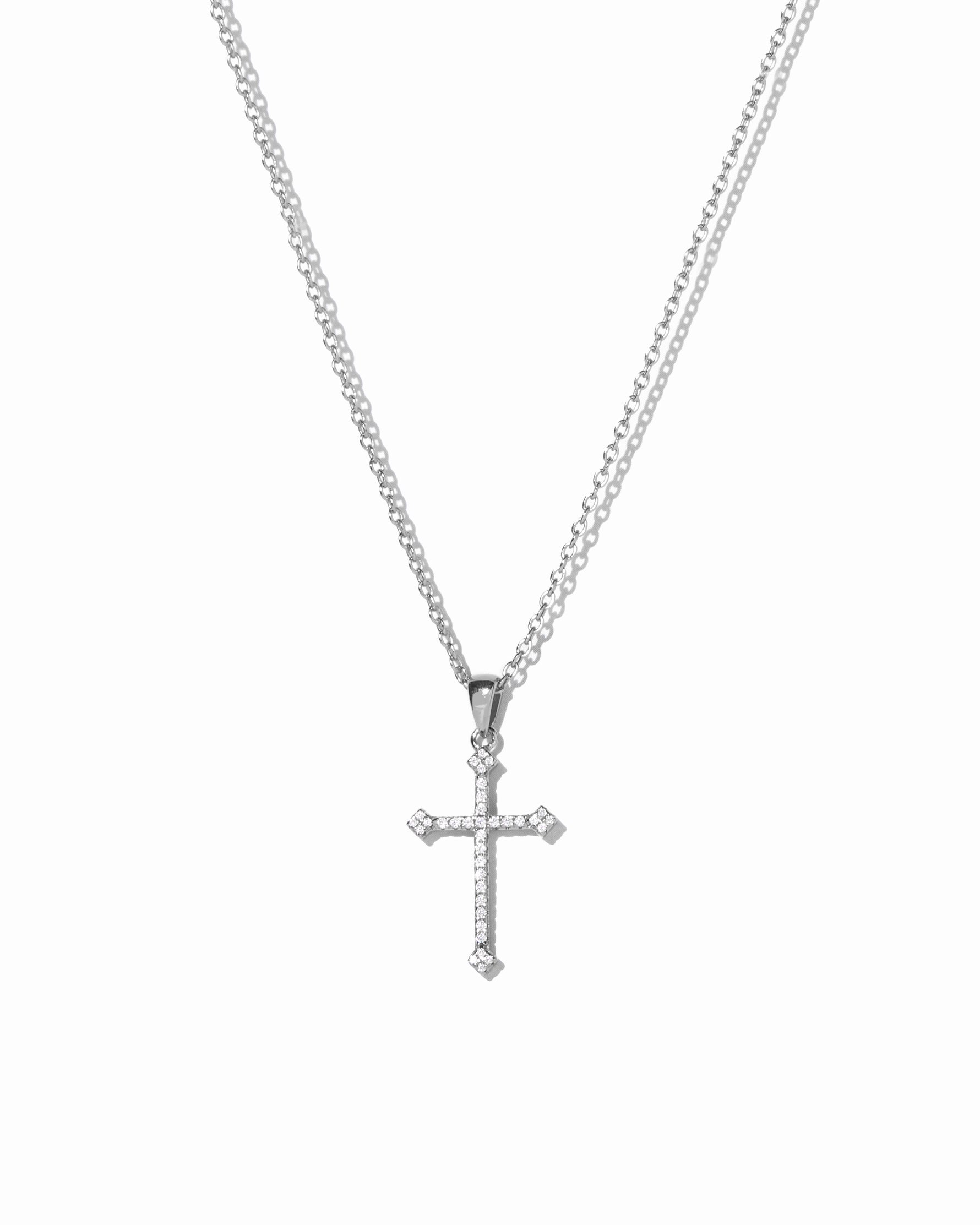 Silver cross pendant necklace on a white background