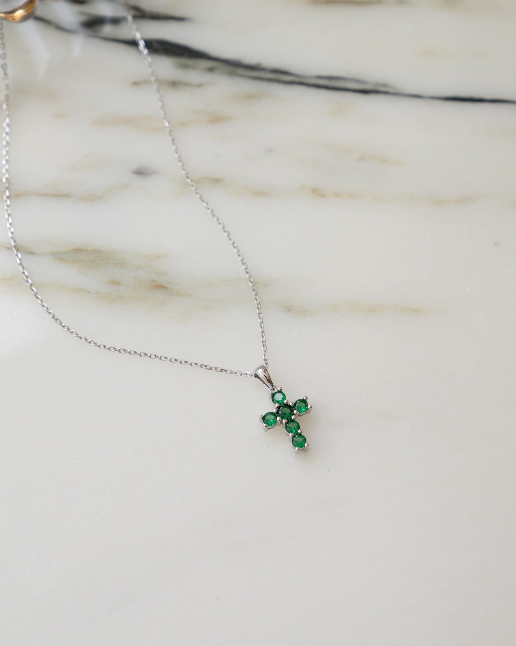 Confirmation gift silver chain necklace with a green gemstone pendant on a marble surface