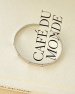 Silver adjustable stacking bangle bracelet on a decorative book