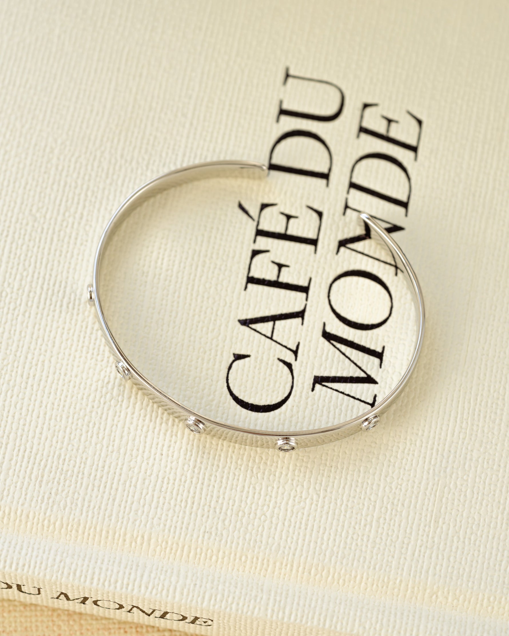 Silver adjustable stacking bangle bracelet on a decorative book