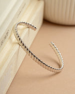 Silver arm cuff bracelet lying against a decorative book