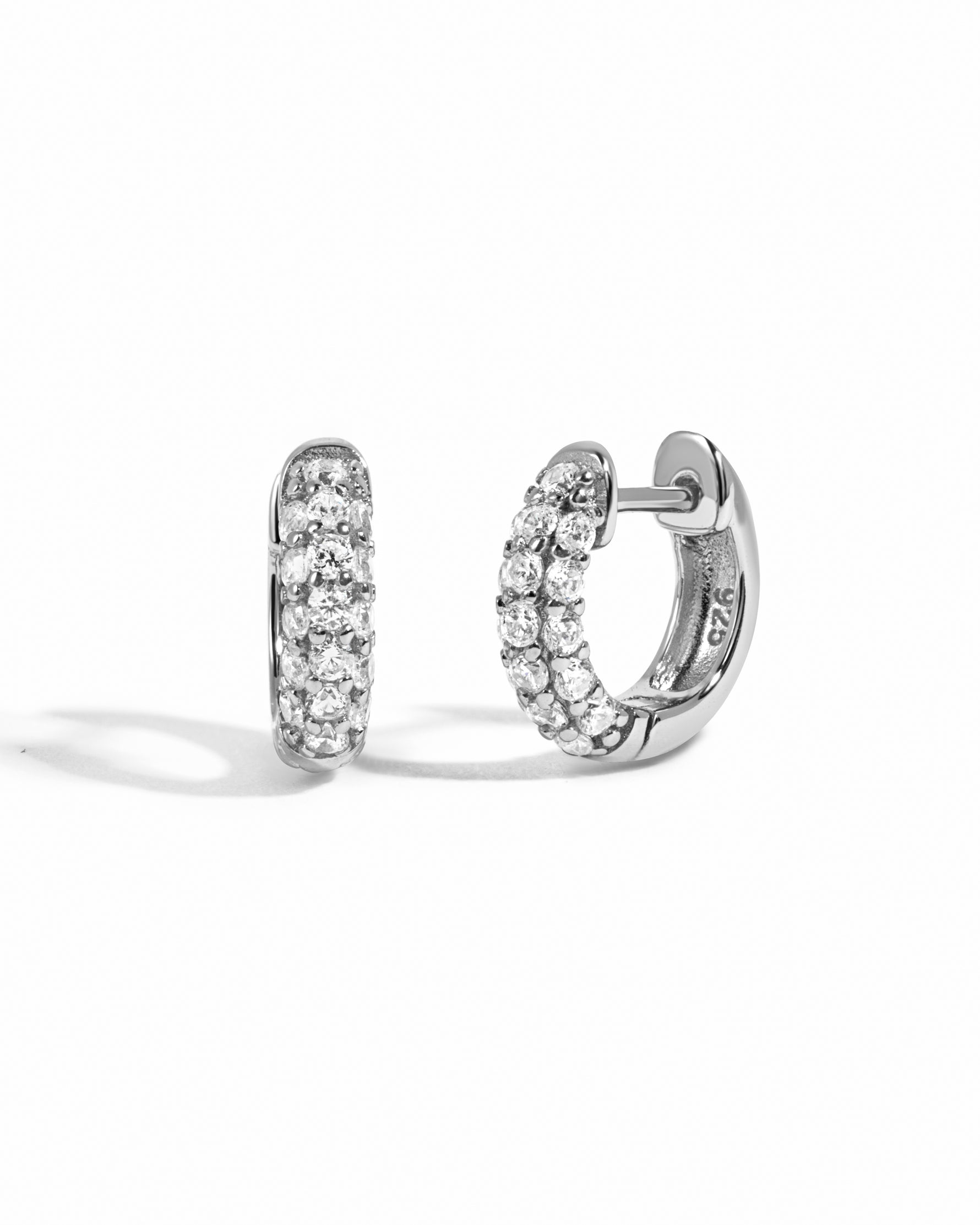 Pair of sterling silver hoop earrings with cubic zirconia gemstones on a white background
