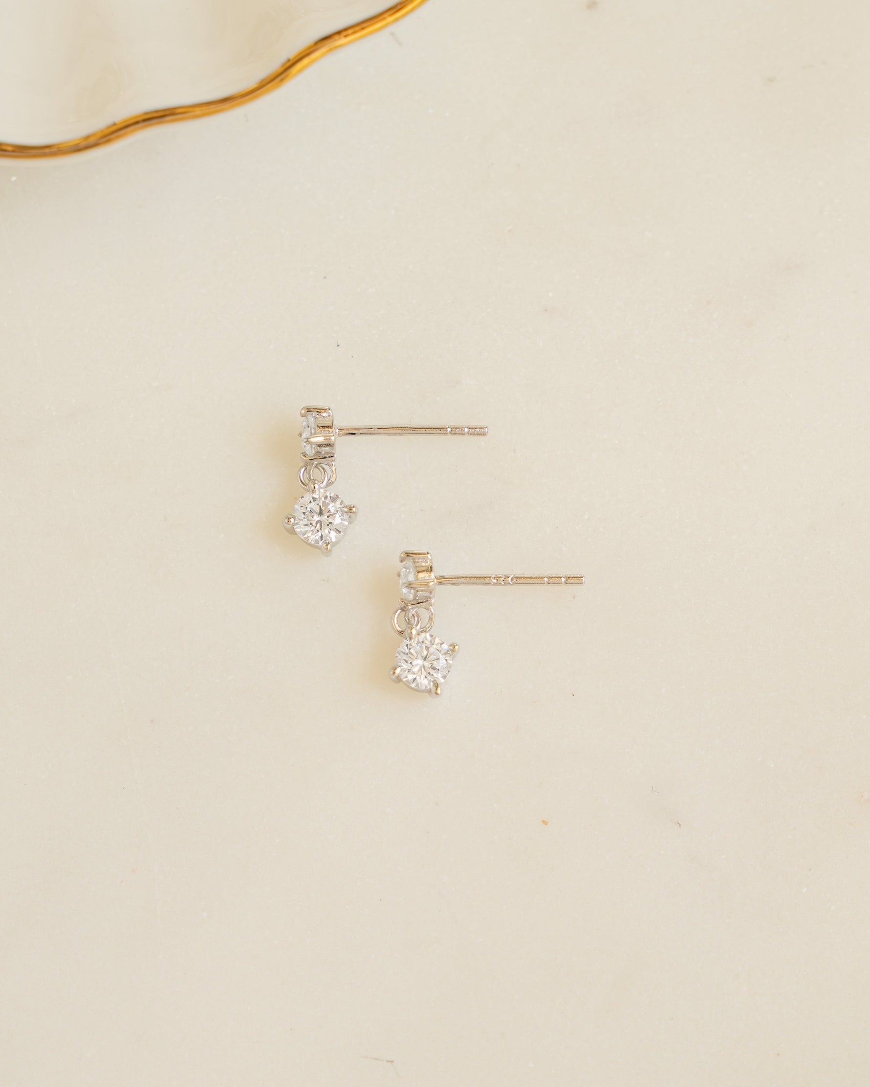 Sterling silver cubic zirconia earrings laying on its side on a plain background
