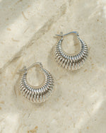 Pair of silver chunky vintage earrings on a neutral background
