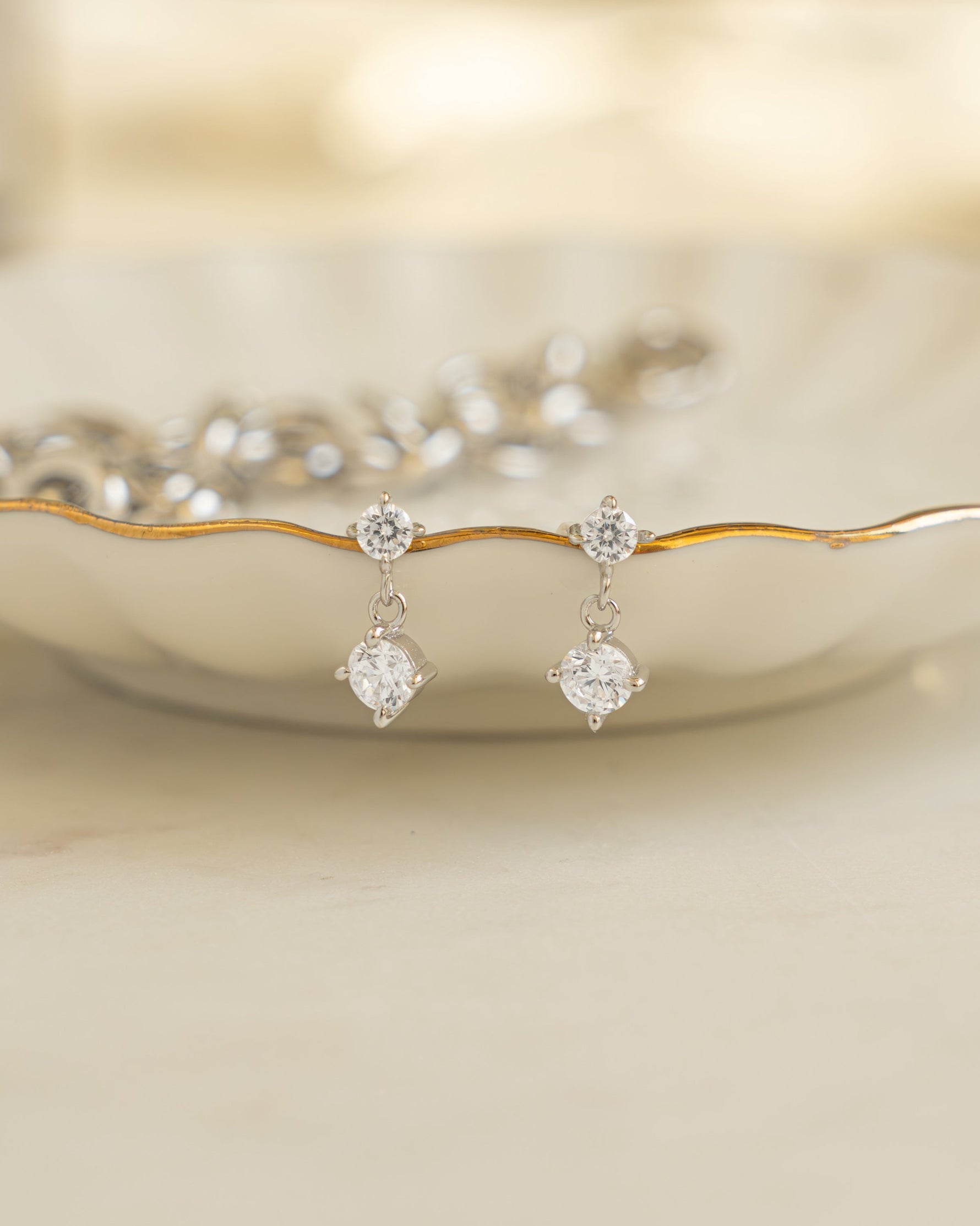 Silver bridal jewelry featuring diamond earrings on a decorative plate 