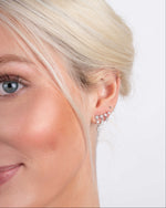 Model wearing silver dangling earrings and a ball stud earring 