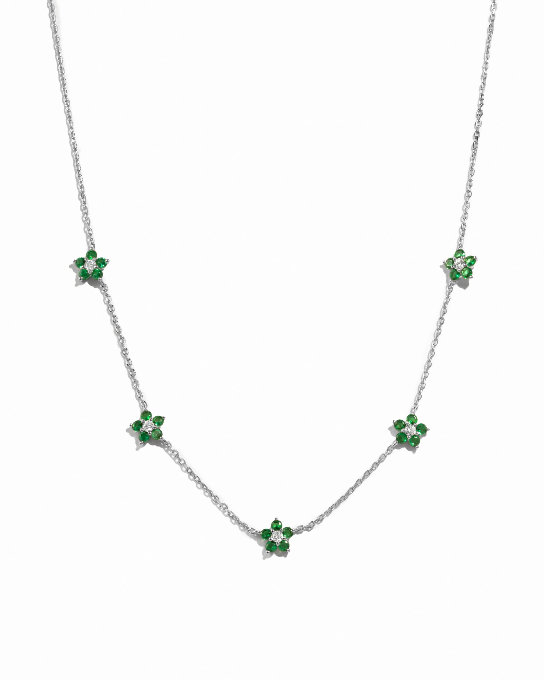 silver flower necklace with emerald green gemstone pendants on a white background