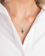 Model wearing religious jewelry featuring and emerald green cross pendant