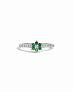 Silver ring with green gemstones and white diamonds on a white background
