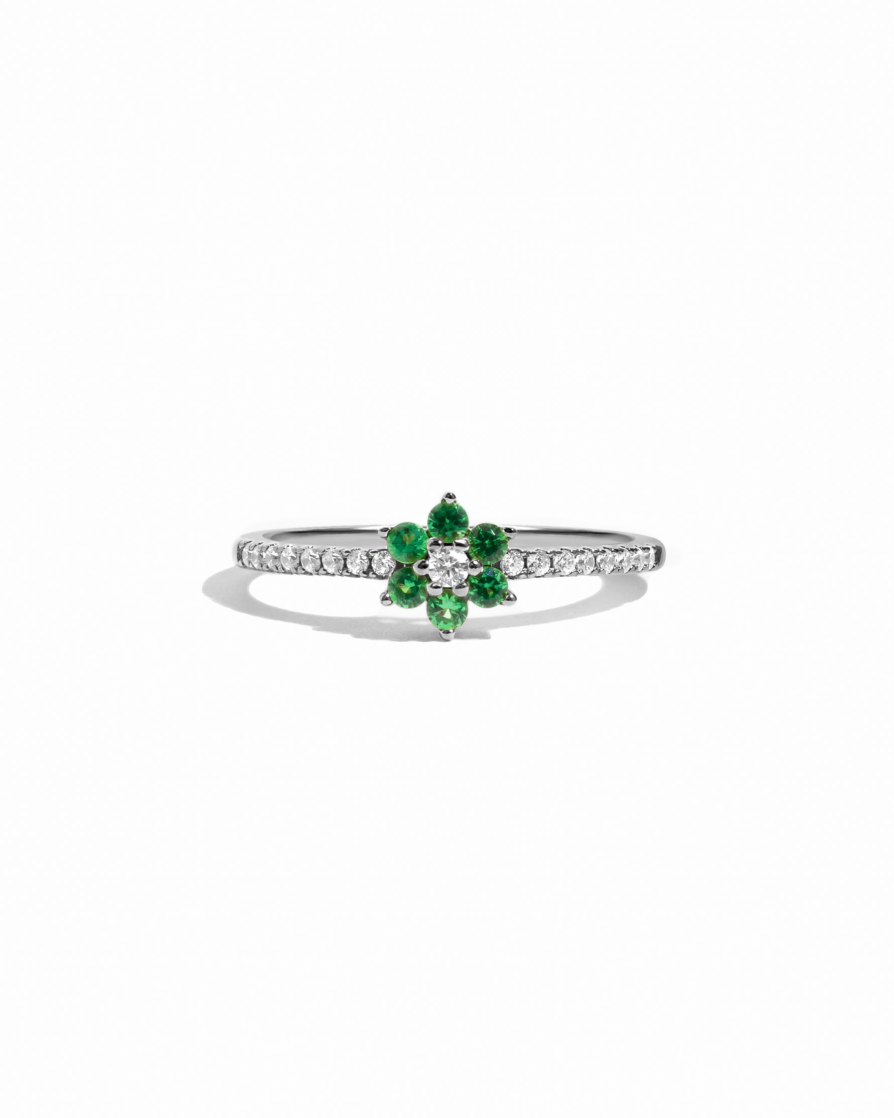 Silver ring with green gemstones and white diamonds on a white background