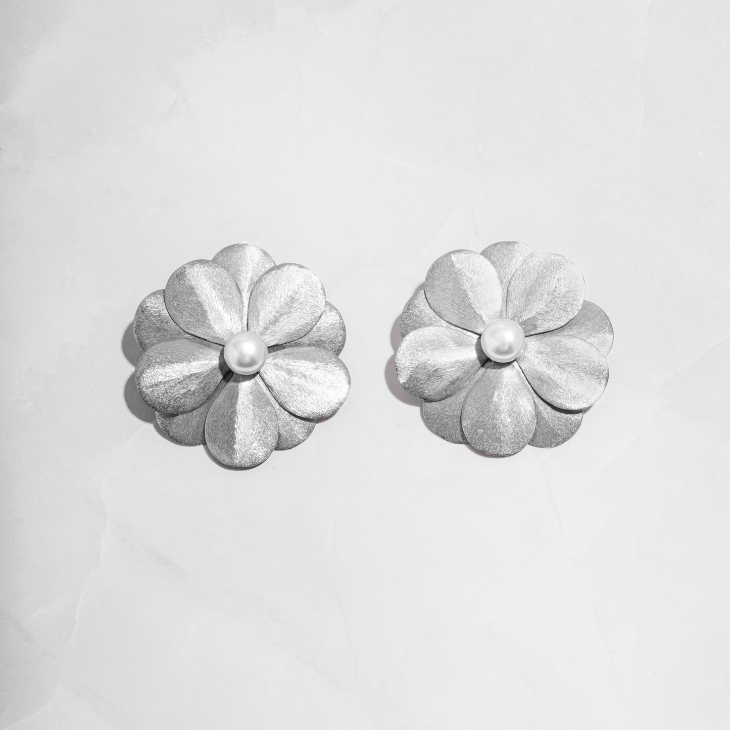 closeup of statement earrings featuring silver flower earrings