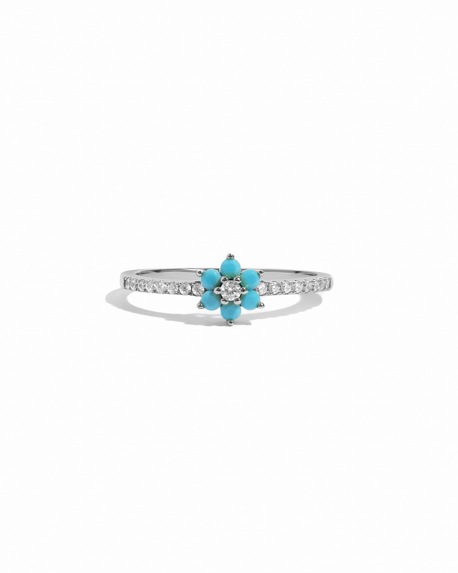 Ring with turquoise flower-shaped gem and white diamond accents on a white background