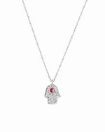 Silver necklace with a hamsa hand pendant featuring a red gemstone on a white background