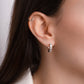 Model wearing silver small hoop earrings with heart bezels. 