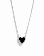 Close-up of black heart necklace with diamond studs outlining its shape, set in sterling silver