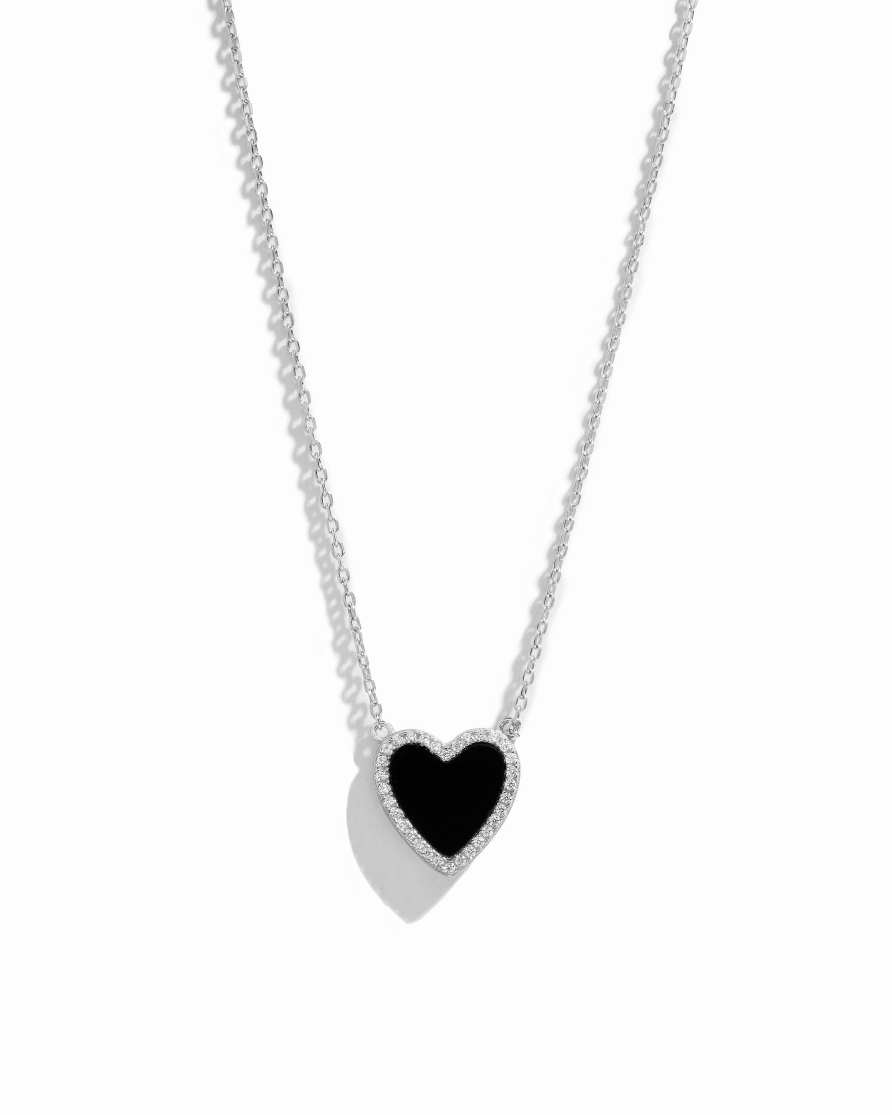 Close-up of black heart necklace with diamond studs outlining its shape, set in sterling silver