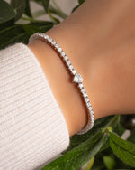 Silver tennis bracelet with a heart-shaped diamond on models wrist