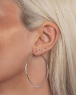 Close-up of model styling large thin hoop earrings in sterling silver, designed as timeless everyday earrings with a minimalist look.