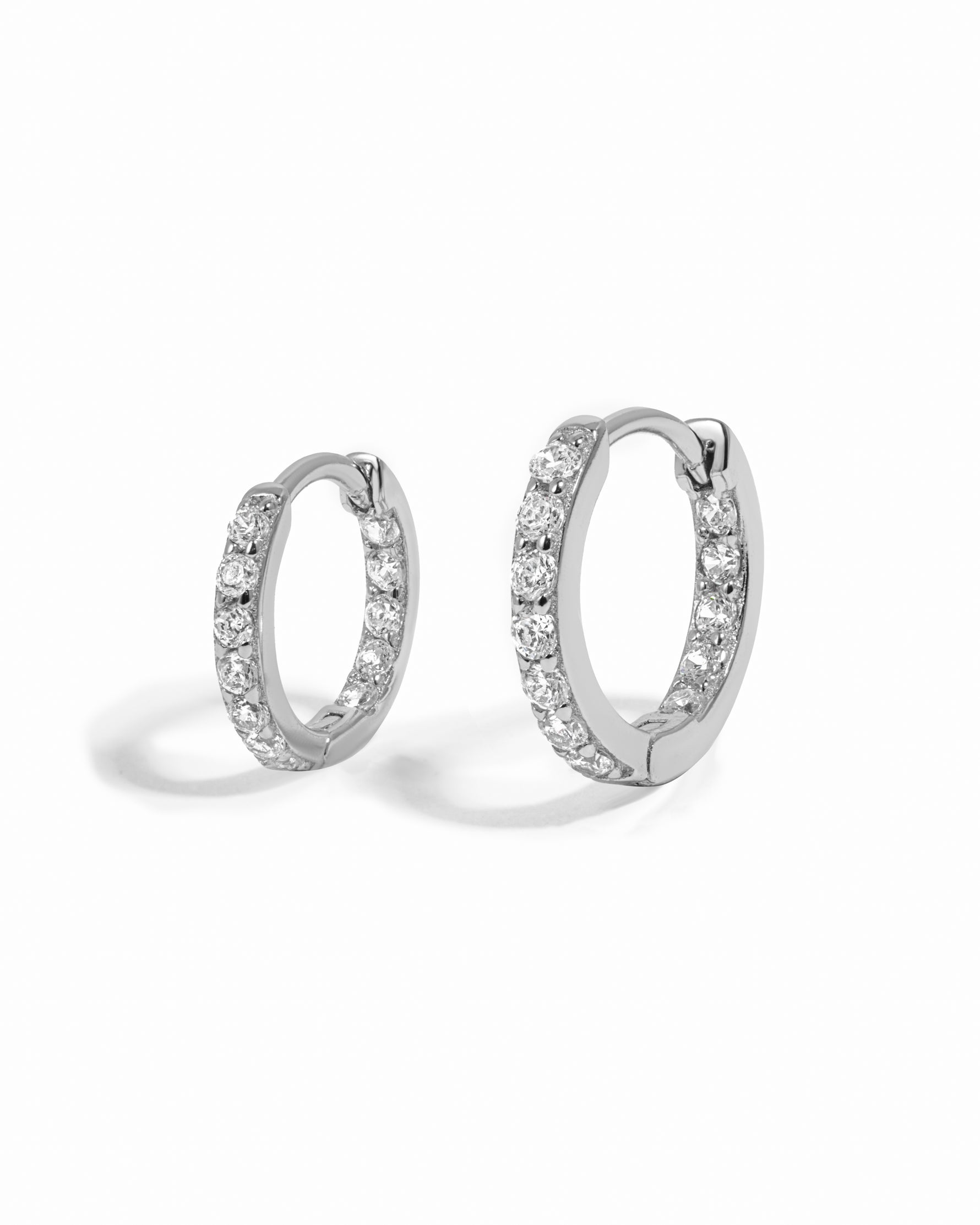 Pair of silver small hoop earrings with cubic zirconia stones on a white background