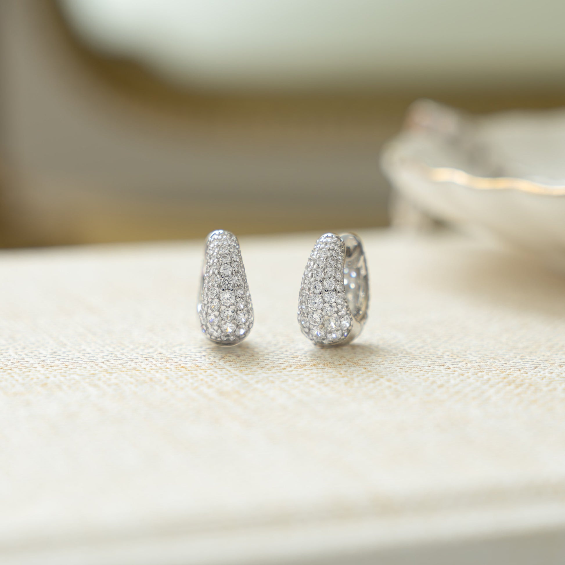 closeup image of small silver huggie hoops with cubic zirconia diamonds  