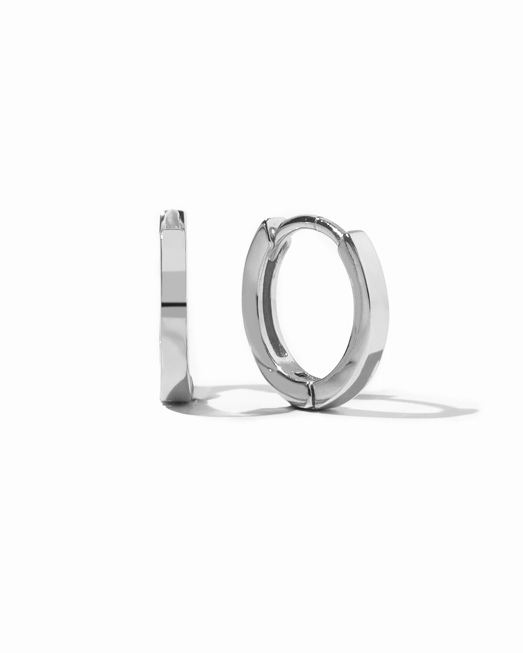 Silver huggie earrings on a white background