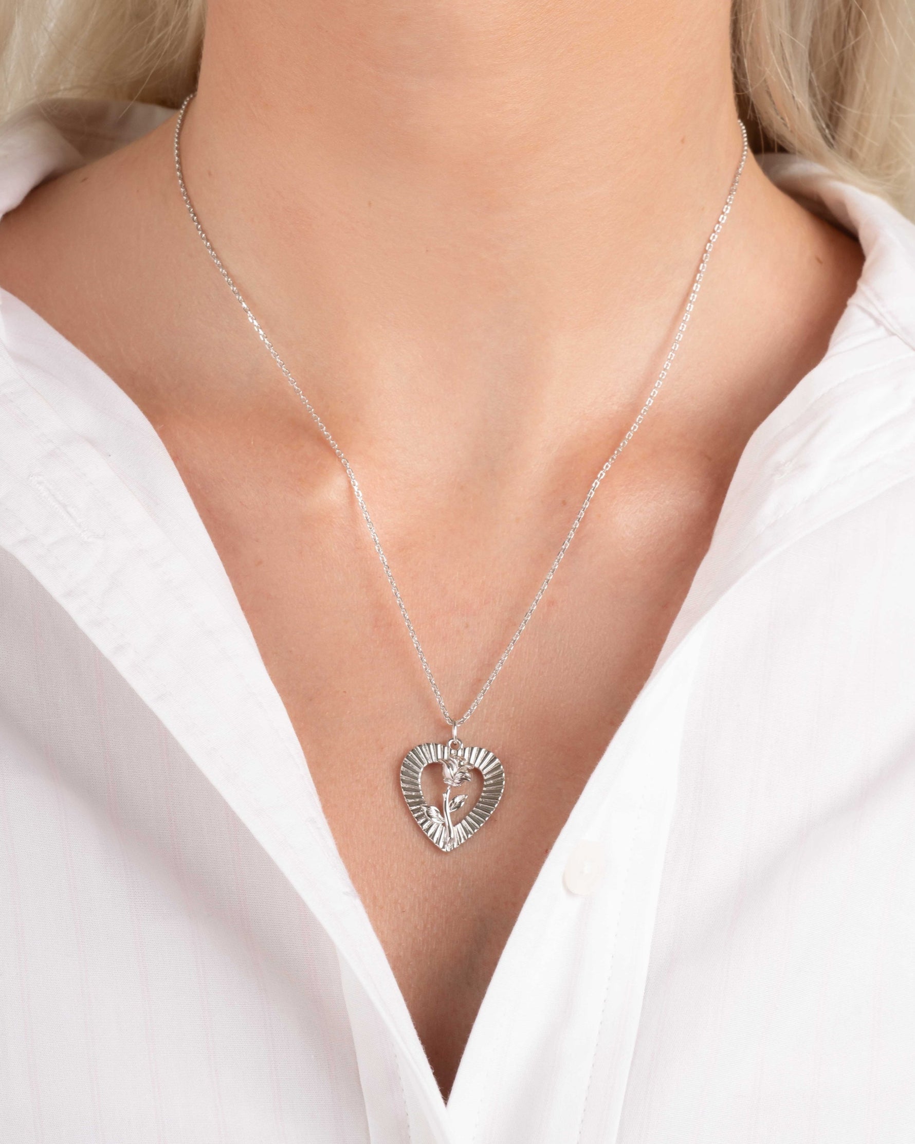 Model wearing vintage charm necklace with a heart pendant on a silver chain on model
