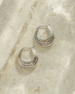 Silver chunky hoops on a textured surface