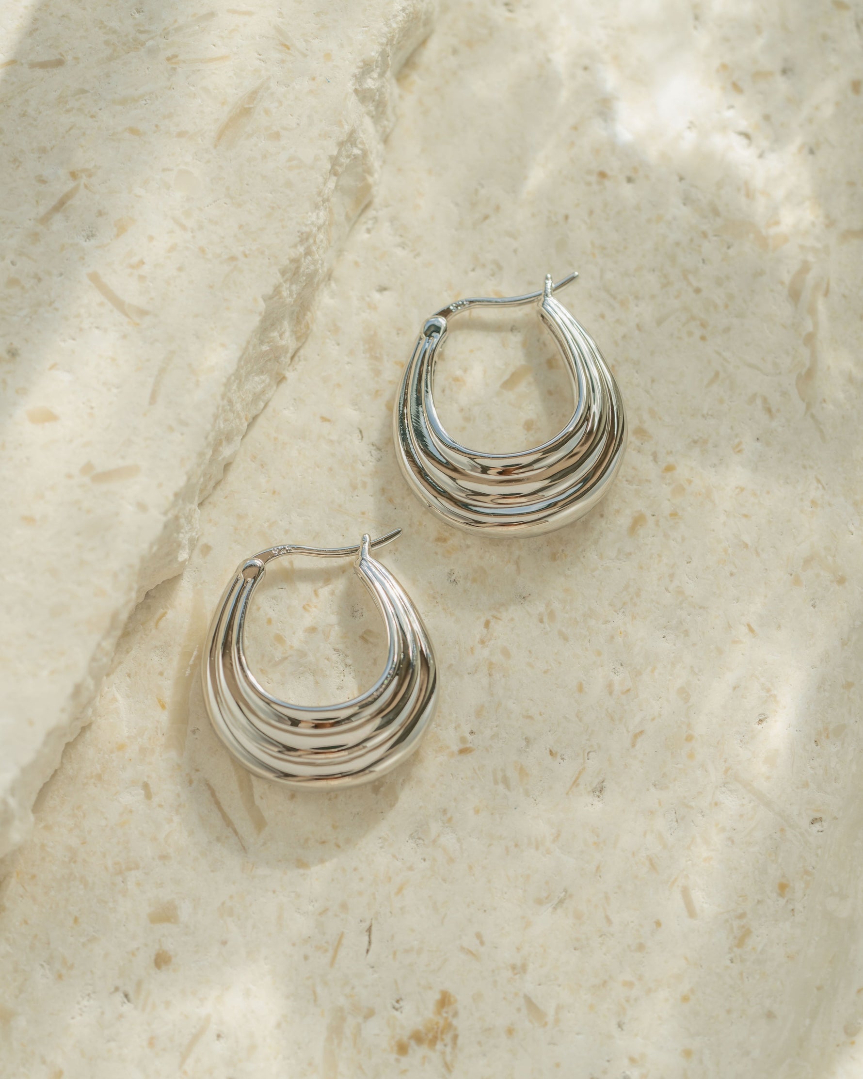 Silver chunky hoops on a textured surface
