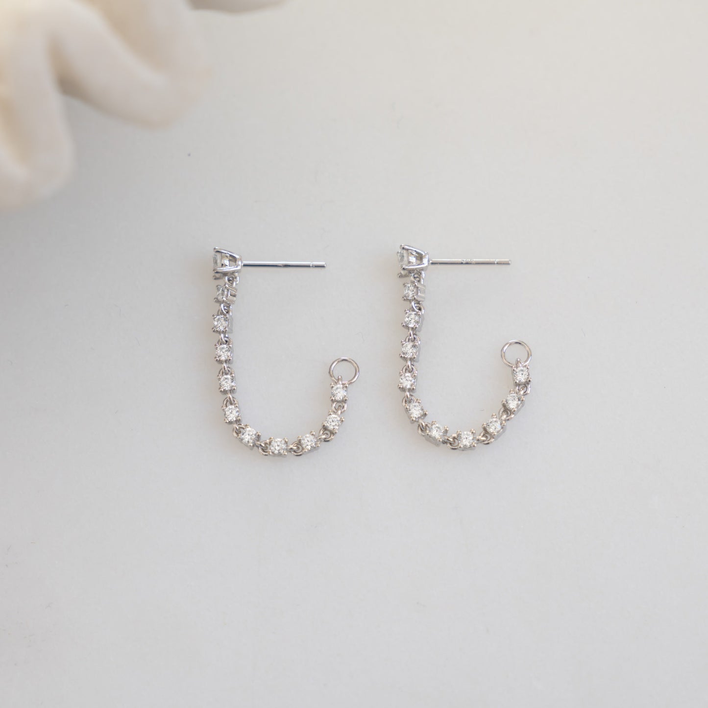 close up of silver front-back dangle earrings with tennis chain accents.