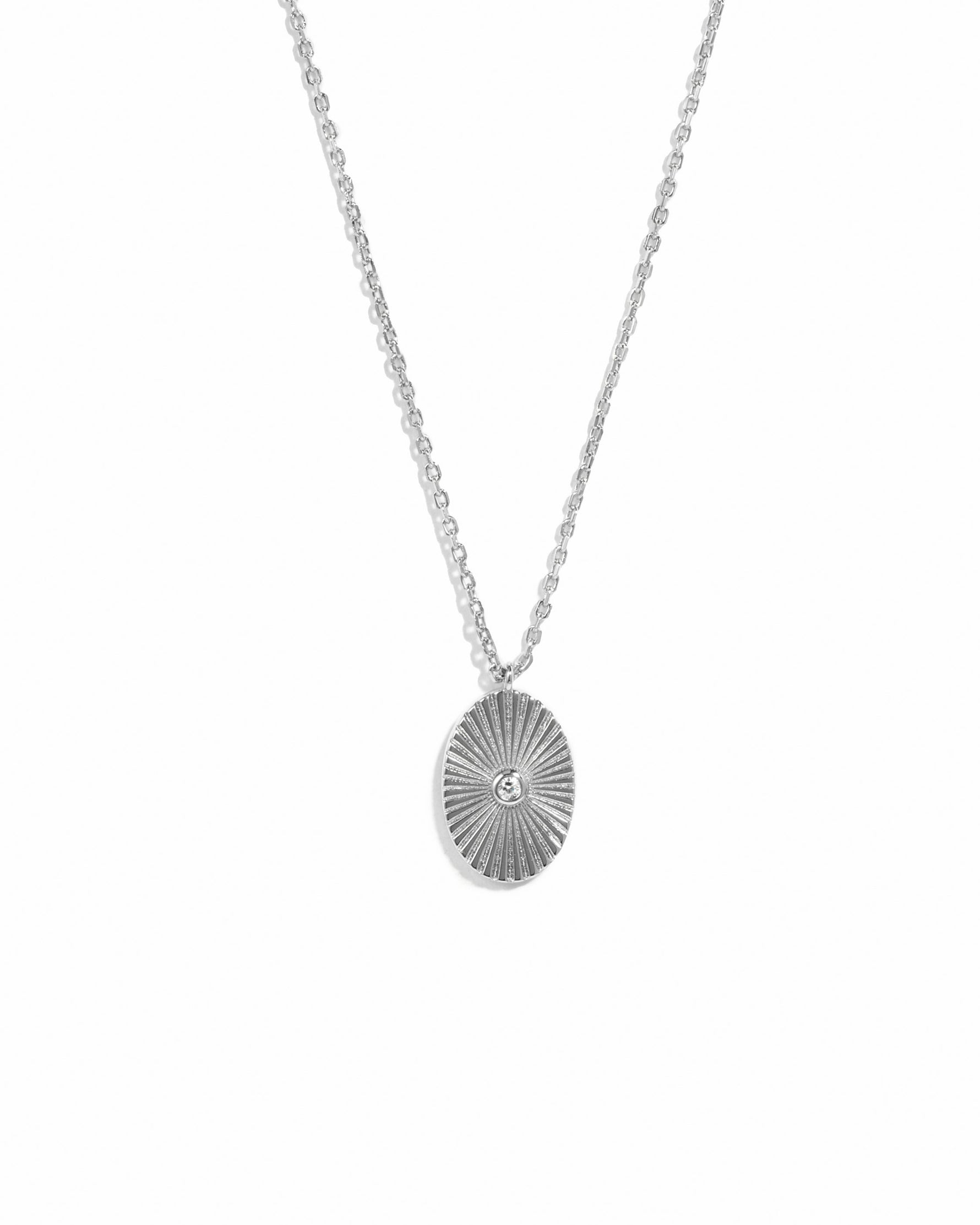 Silver necklace with a circular pendant on a white background